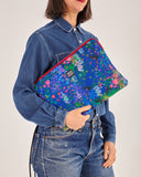 Funda de laptop 13" con estampado original hecha de tejidos de botellas recicladas, estampado Nuria Flores, diseño original de flores coloridas sobre un fondo azul,  moda sostenible