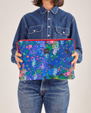 Funda de laptop 13" con estampado original hecha de tejidos de botellas recicladas, estampado Nuria Flores, diseño original de flores coloridas sobre un fondo azul,  moda sostenible